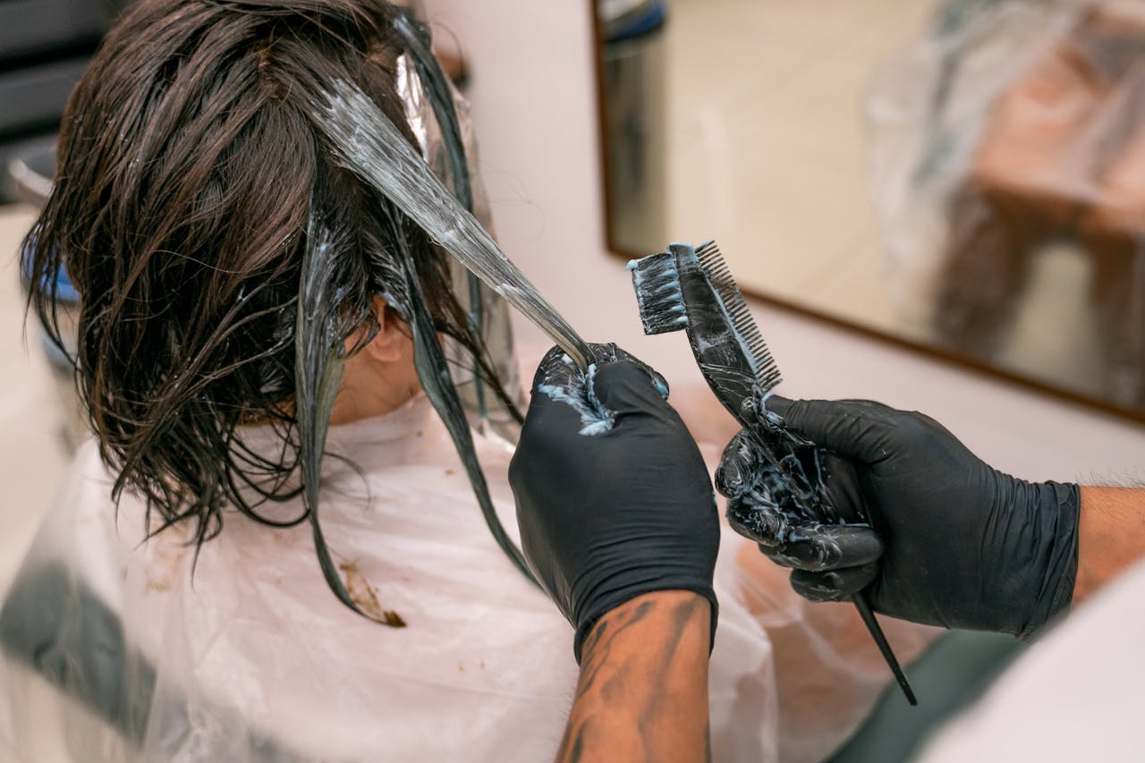 Services-03 Close-up of hair coloring process in a salon. Hairdresser applying dye to client's hair.